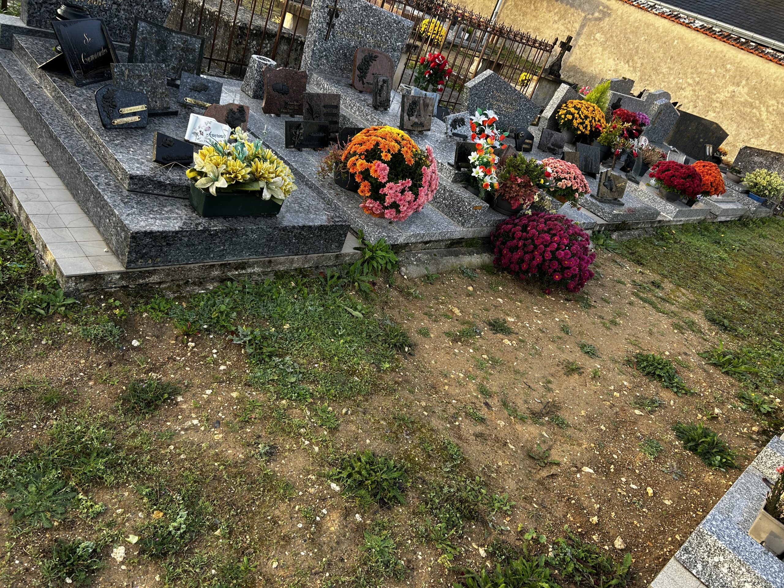 Plaques funéraires et bouquets de fleurs disposés sur une tombe en granit, en hommage à des proches disparus.